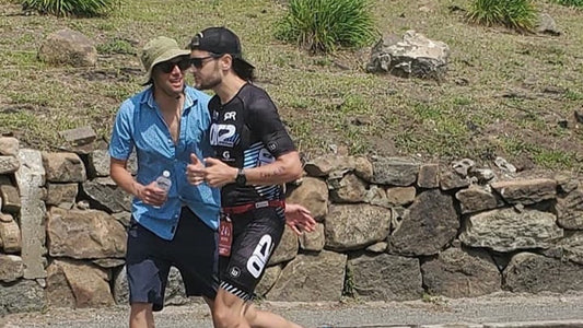 A QT2 athlete running during a race while his coach runs alongside and talks with him.